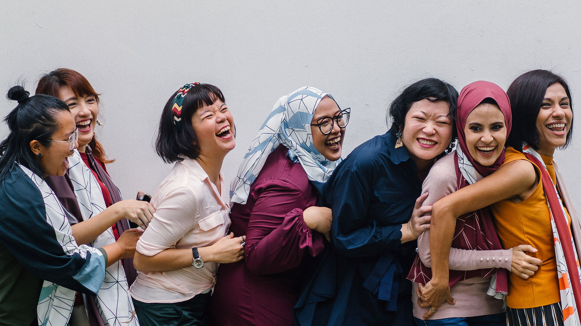 Group of women in a row laughing while taking a picture