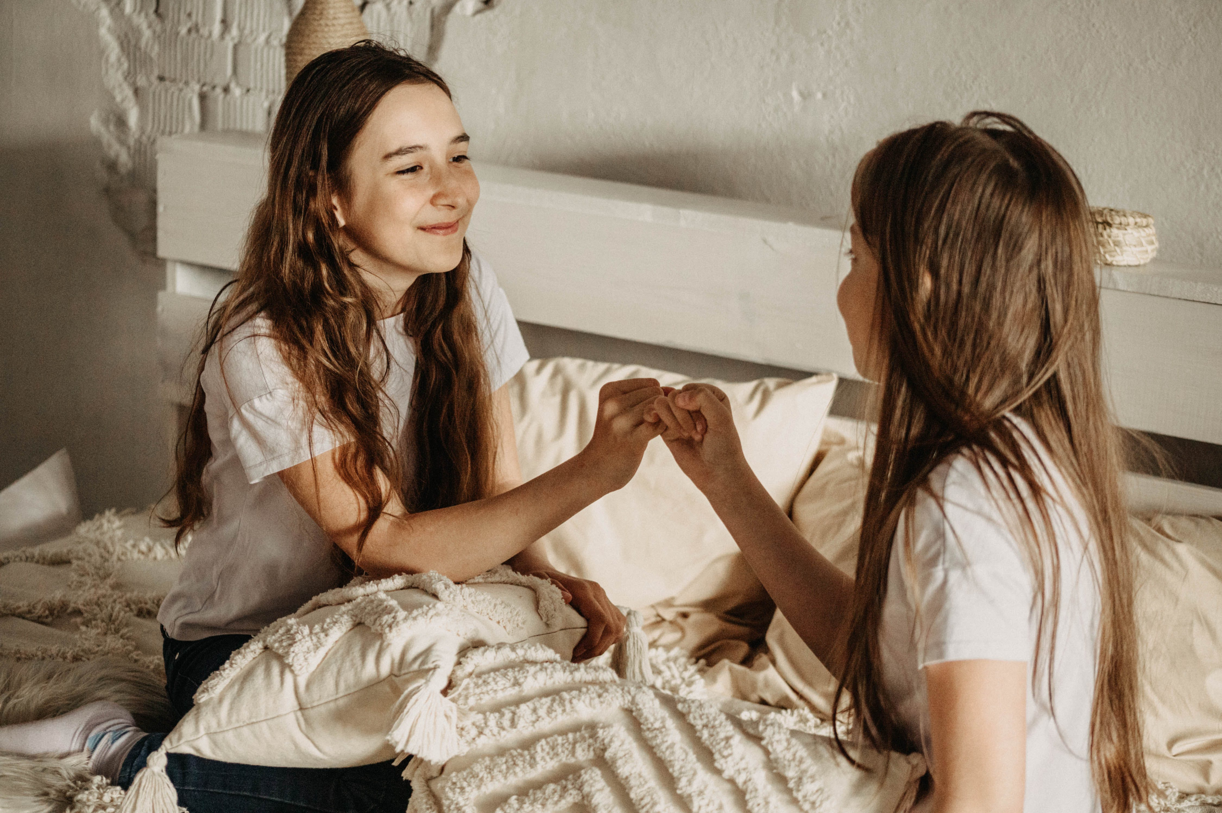 Two young girls playing pinky swear